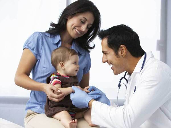 A friendly Scripps Health doctor engages with a small child and her mother in a clinical setting. 